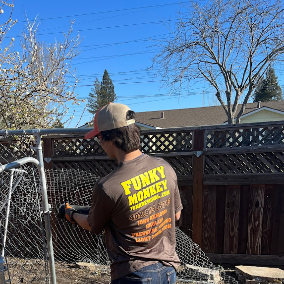 Man cutting down a chain link fence